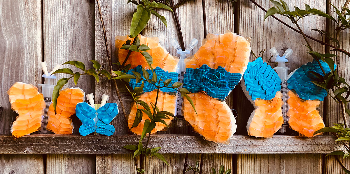 four colorful plastic butterflies sitting on a wood fence