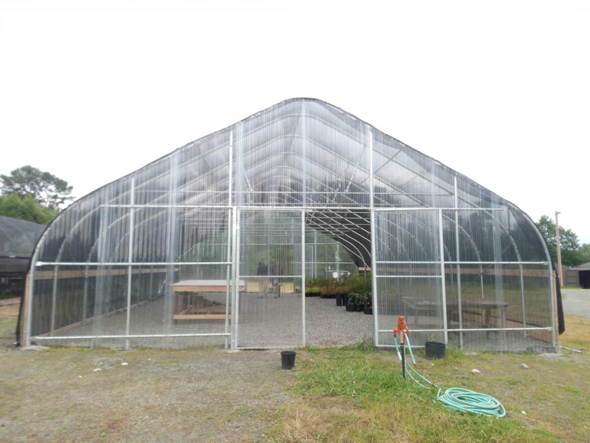 Photo of a hoop-style greenhouse with an open door.