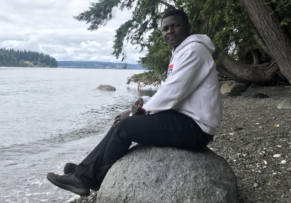 Francis Abugbilla sitting on a rock by water