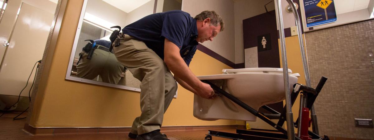 Photo of a person installing a toilet in the UW Tower.