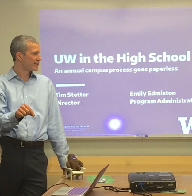 Tim Stetter in front of a projection screen showing his UW in the High School presentation.