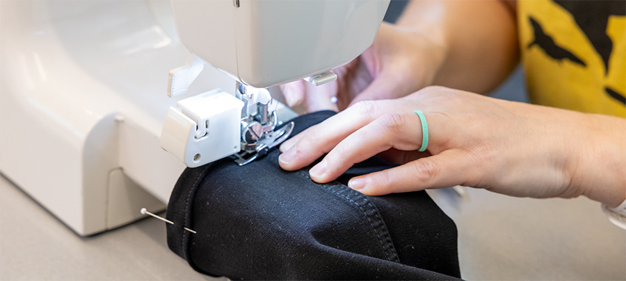 a person's hands sewing a pair of pants