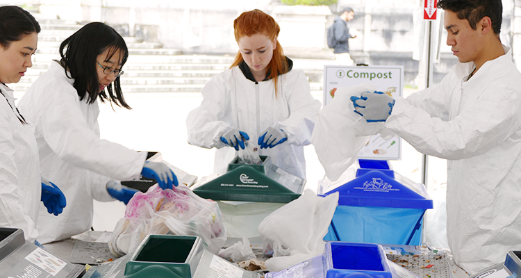 people wearing full body white plastic suits sorting through trash