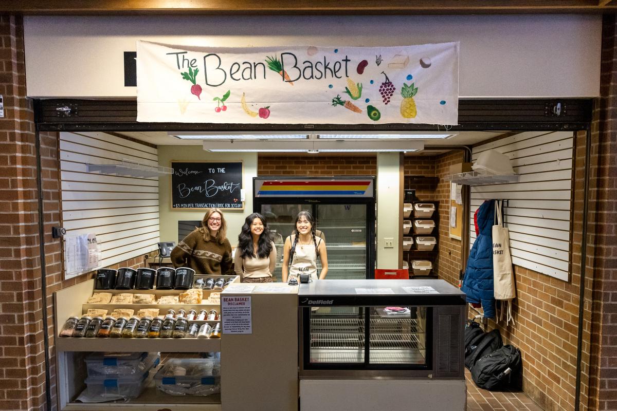 three students in front of the uw bean basket