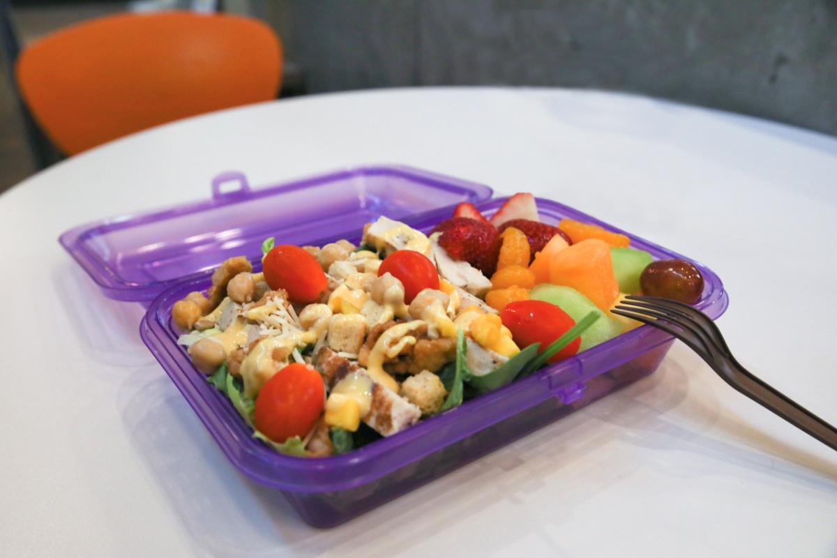 purple reusable container with a salad and fresh fruit inside