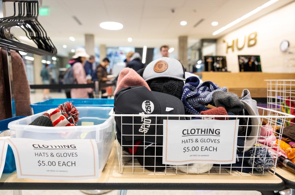 variety of clothing items in a basket on a desk next to some clothes hangers