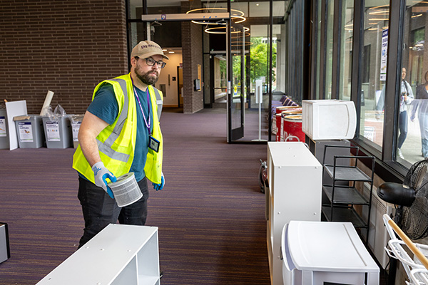 person with a high-visibility vest moving a small item over to several storage drawers in a residential space
