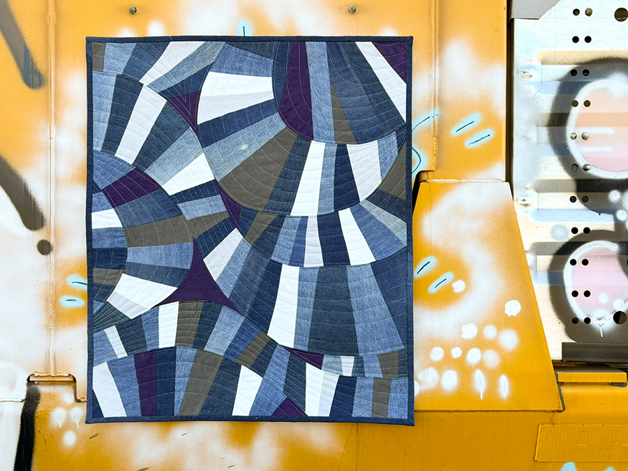 a handcrafted quilt with a series of arcs and circles with distinct jean texture