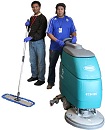 Two custodians, one with a dry mop and the other with a floor buffer