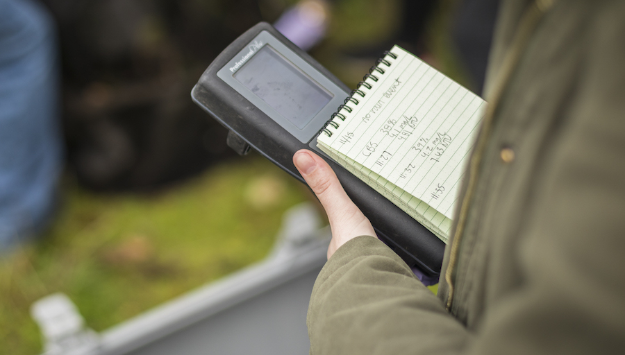 close up of a hand holding a notebook and monitoring device