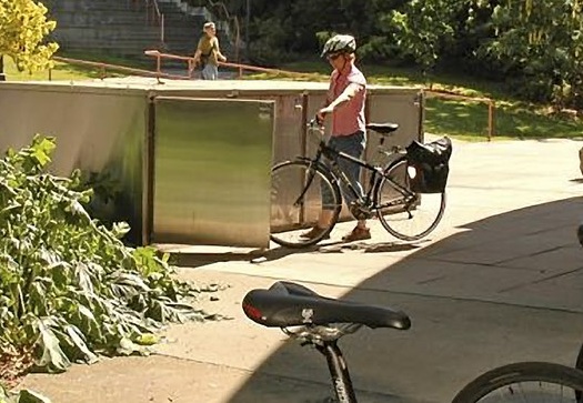 A cyclist uses a bike locker on campus