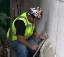 A worker in a high viz vest and hard hat focuses on a task