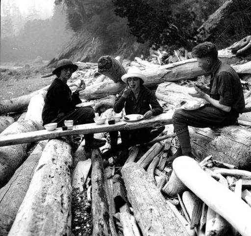 old black and white photo of students eating on a beach