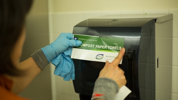 UW staffer placing "Compost paper towels" sticker