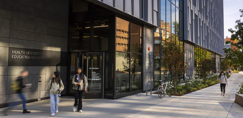 students walking on sidewalk outside new Health Sciences Education building