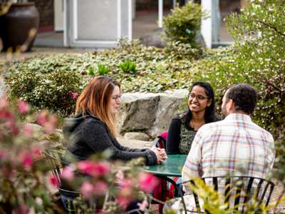 faculty and staff talking at an outdoor table