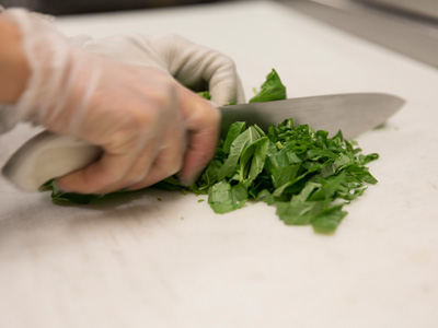 hand with knife chopping fresh greens