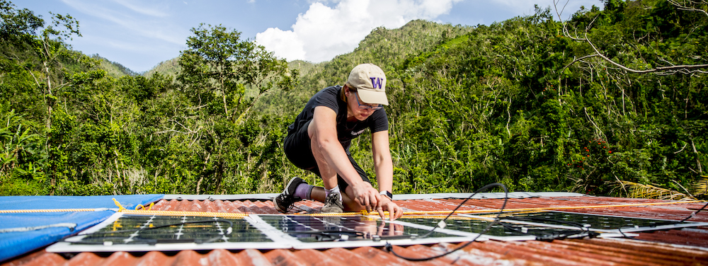 person with a UW hat installing a solar panel on a roof in Puerto Rico